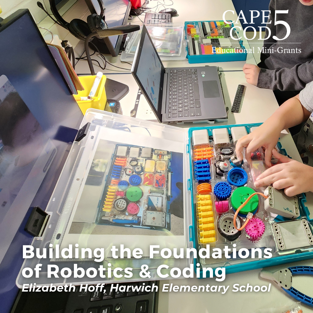 Student building Vex Go robot in classroom with laptops