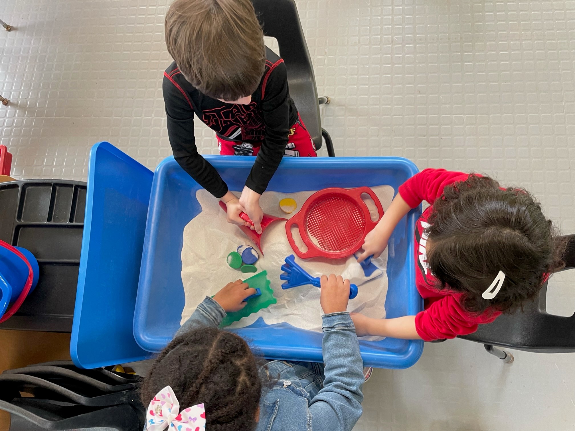 Sensory table with sand that children are playing with to learn about the various states of matter.