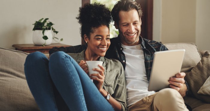 Smiling couple sitting on couch with iPad