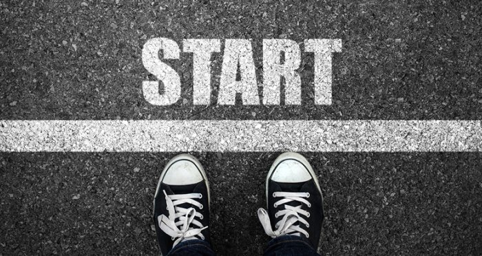 Person wearing sneakers at a starting line with the word start painted on the road