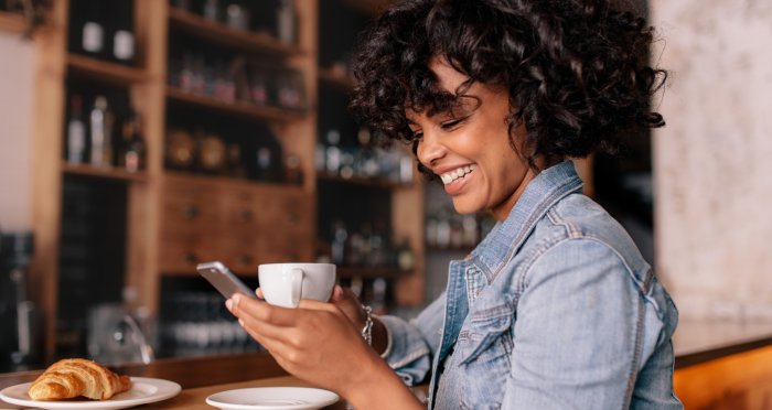 Woman at cafe banking on phone smiling