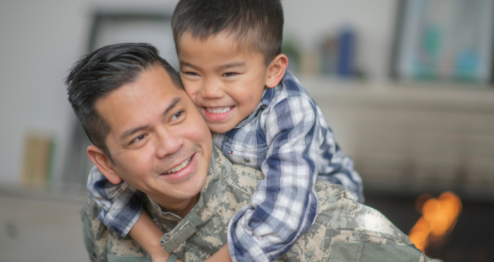 A military dad and his son hugging in living room
